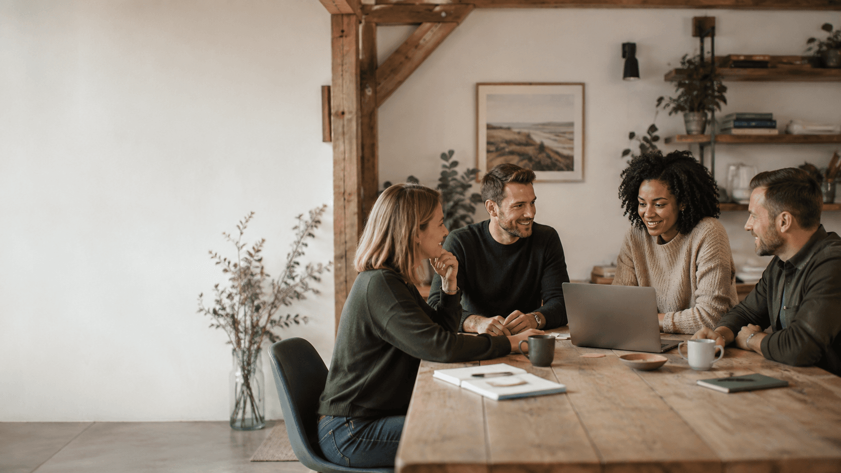 A diverse team collaborating around a laptop in a warm, people-centred workspace